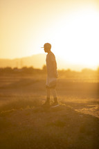 a teen boy standing in warm sunlight 