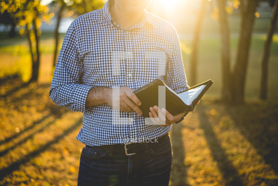 a man holding a Bible outdoors 
