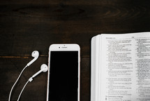 iPhone with earbuds and an open Bible 