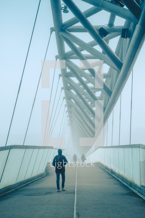 people crossing a foggy bridge in winter 