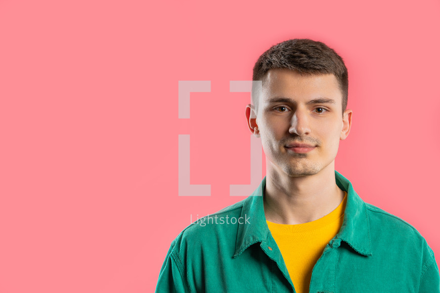 Friendly young man on pink studio background. Copy space. Teenager student guy. High quality photo