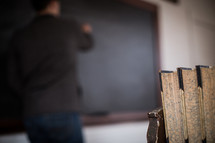 teacher writing on a chalkboard in classroom. 