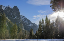 A wilderness scene of mountains, trees, and snow.