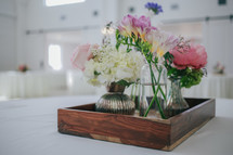 flowers in vases on a tray on a table 