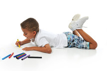 Boy laying on the floor coloring with markers.