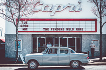 vintage Studebaker parked in front of a cinema marquee sign 