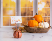 Orange and white pumpkins with a blessed sign in front of autumn window