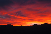 A vibrant and breathtaking sun rises over the ridge of a mountain.