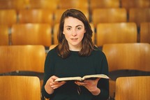 a woman reading a Bible alone in a church 