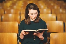 a woman reading a Bible in a church alone 