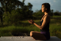 a woman doing yoga and meditating outdoors 