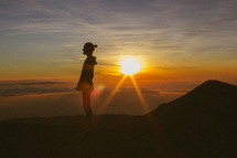 silhouette of a man standing on a mountaintop at sunrise 