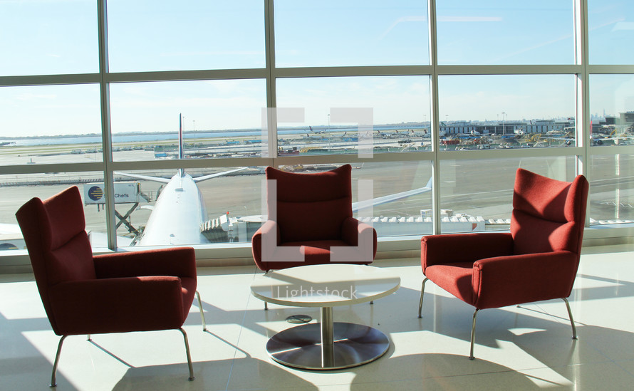 a table and chairs in an airport with a view of the tarmac 