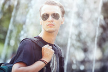 a man in sunglasses holding a backpack 