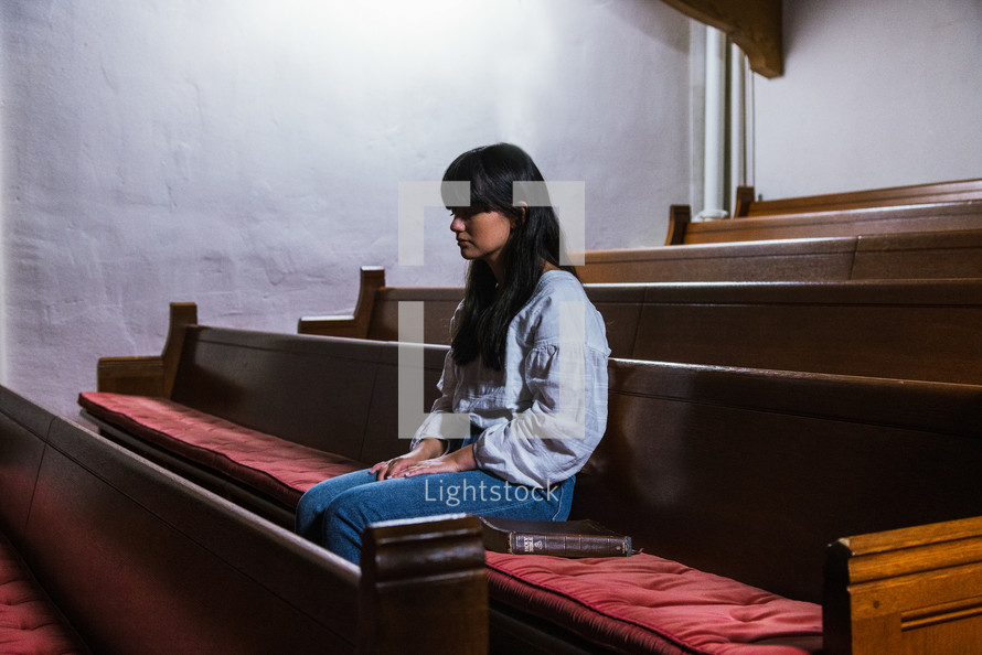a woman sitting alone in a church 