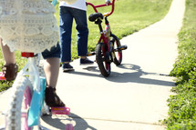 children riding bikes on a sidewalk 