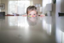 a girl child peeking over a countertop at candy