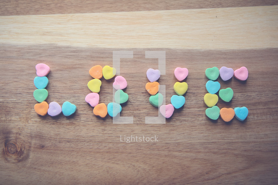 heart shaped candy in the shape of the word love on wood 