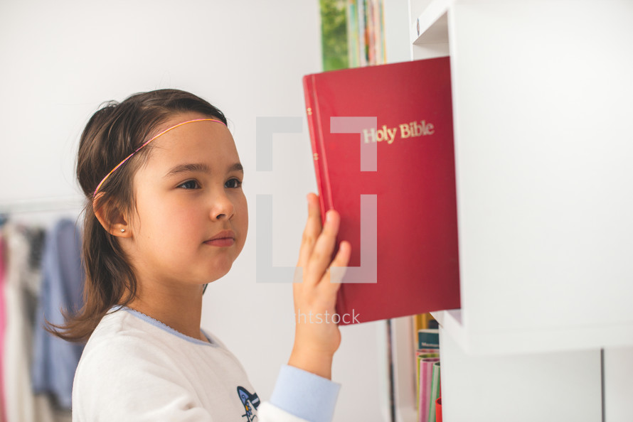 Little girl taking the bible from her library
