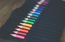 colored pencils in a black apron 