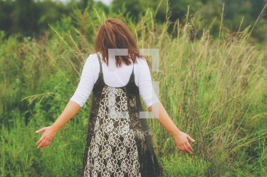 a young woman walking through a field of tall grasses 