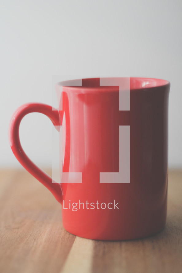 a red mug on a wood table 