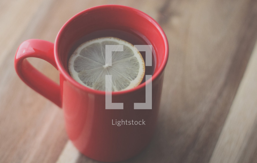 lemon in tea in a red mug 