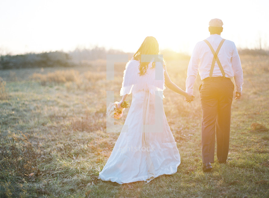 bride and groom walking outdoors holding hands 