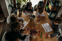 girls and boys coloring on a coloring page at home 