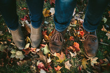 a couple in boots standing in fall leaves 