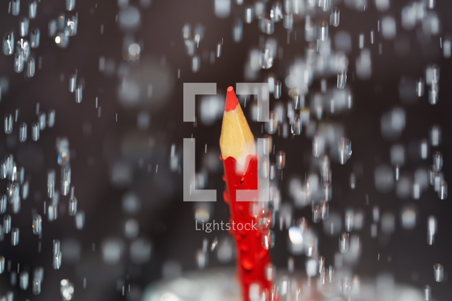 Red colored pencil under the rain