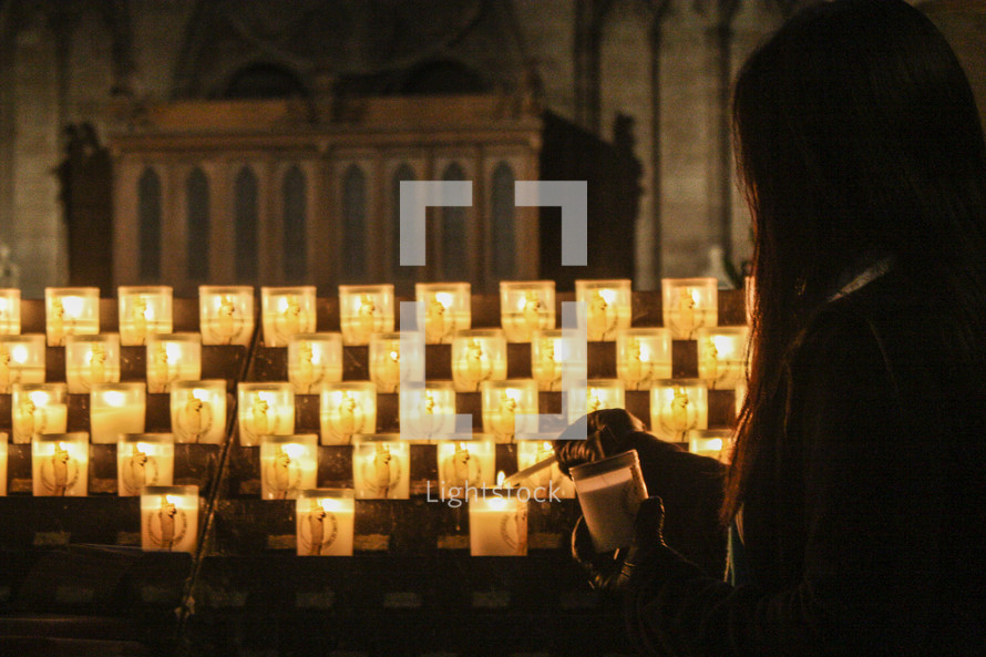 a woman lighting a candle in a cathedral 