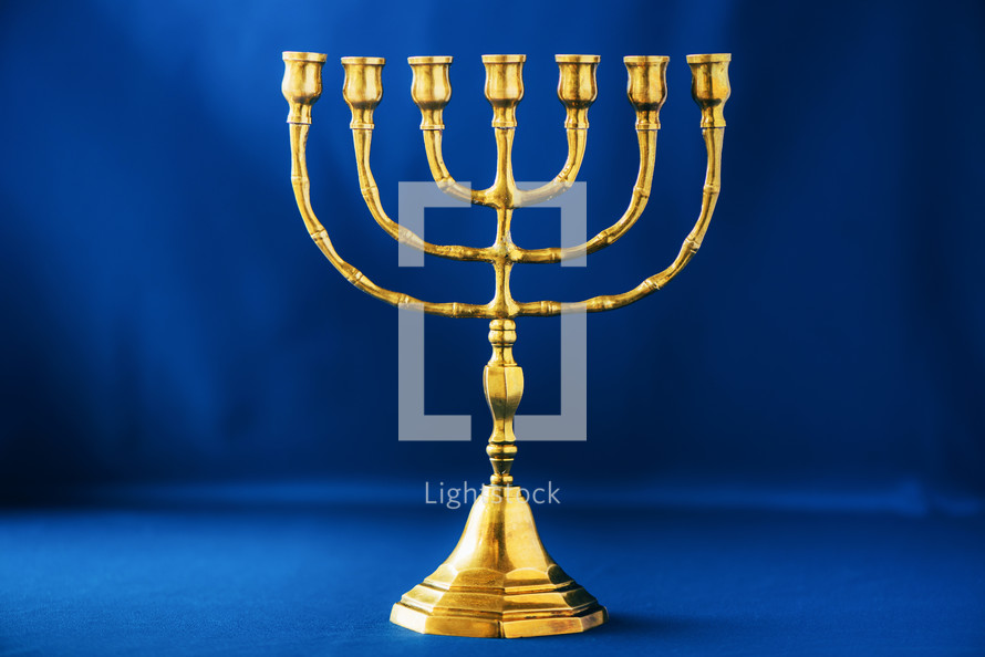 Golden hanukkah menorah on blue background. Jewish holiday banner with copy space. Ancient ritual religious candle menorah