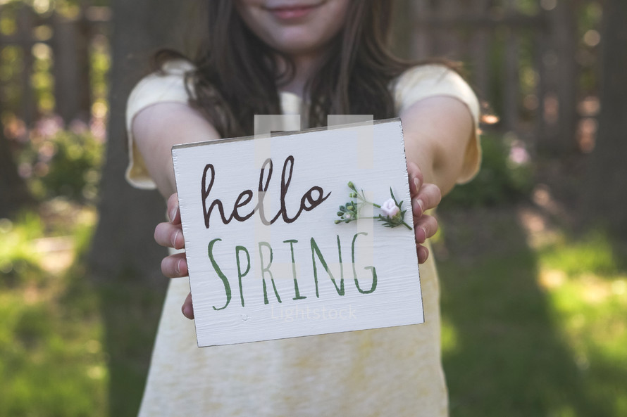 little girl holding a Hello spring sign 