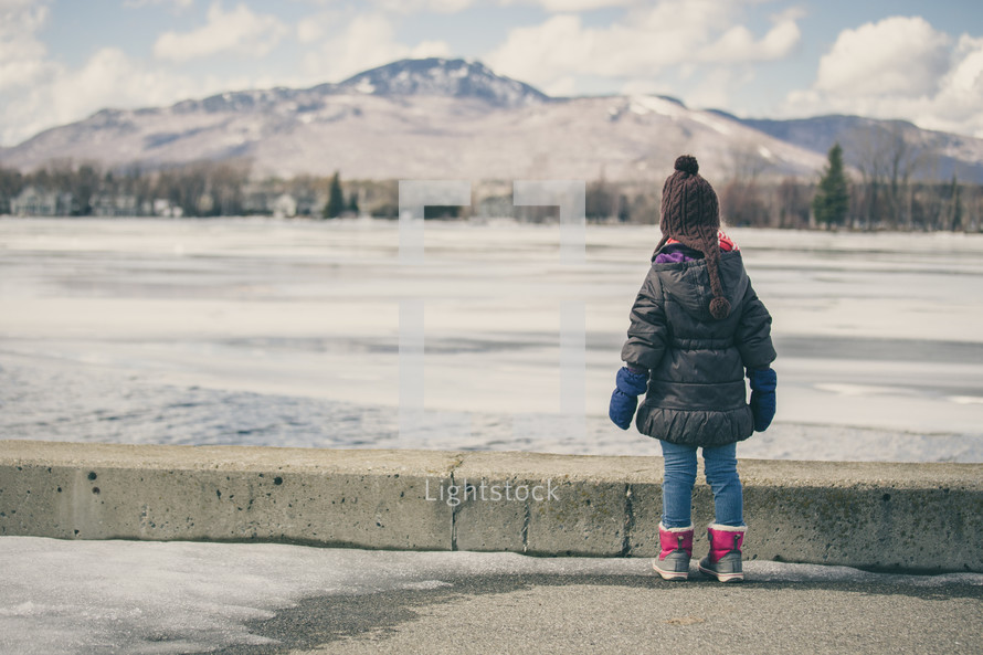 a child staring at a frozen lake 