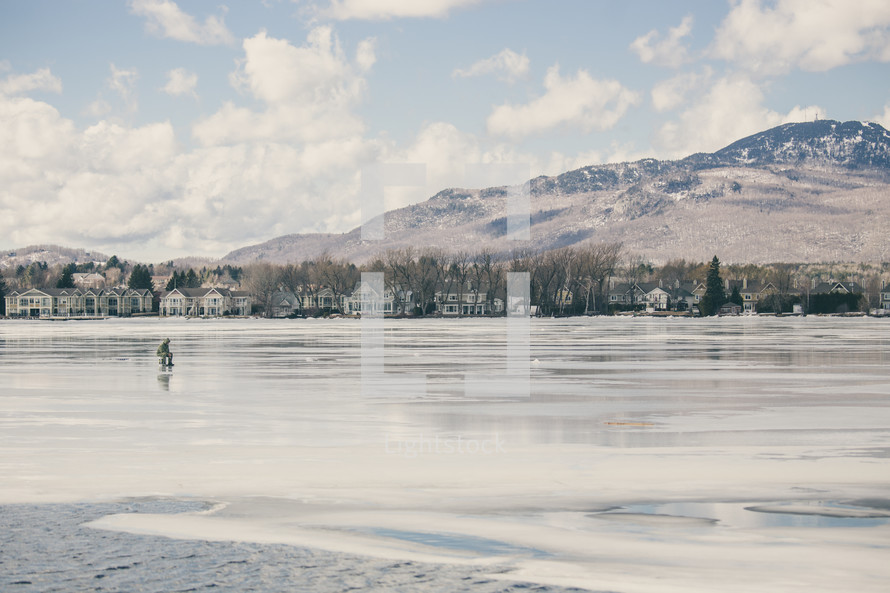 a man sitting on a frozen lake ice fishing 