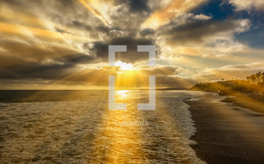 rays of sunlight behind the clouds over a beach 
