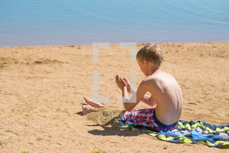 a boy playing in the sand on a beach 
