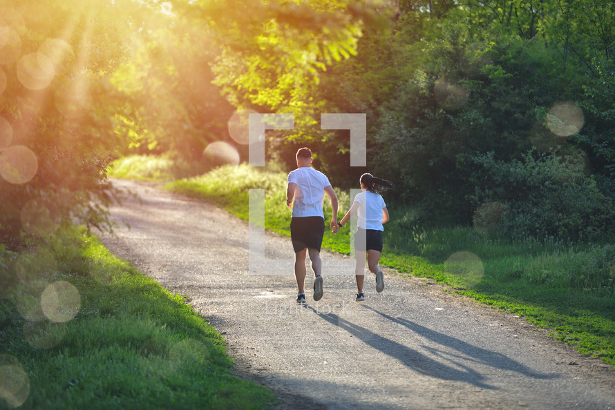 people jogging and exercising in nature, in morning sunrise warm light