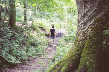 a woman walking in a forest on a trail 