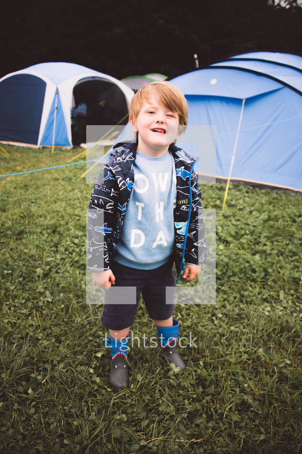 a boy standing in front of tents 