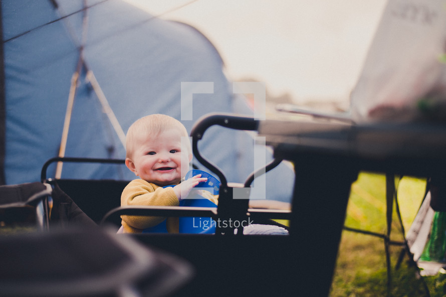 an infant in a wagon in front of a tent 
