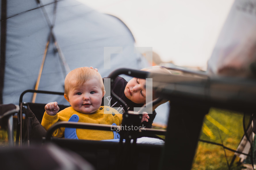 infants in a wagon in front of tents 