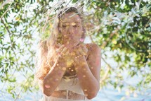 woman blowing glitter from her hands outdoors 