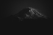 A snow capped mountain peak at night