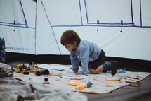 a boy child playing with toys in a tent 