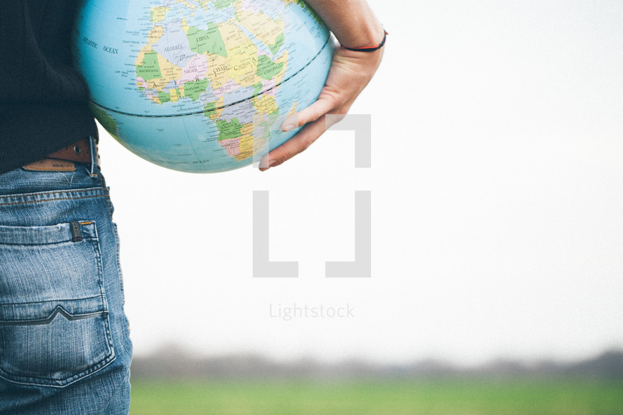 man holding a globe standing in a field