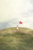 girl walking with red balloons up a hill