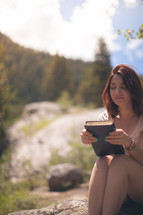 woman looking at her Bible outdoors 