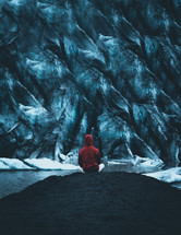 a man sitting in front of an iceberg 